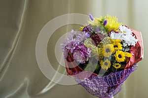 Flowers of different colors  in the bouquet on the background of green curtain. Rose, chrysanthemum, aster, carnation