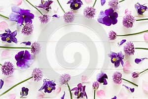 Flowers flat design, purple  and pink  flowers on white wooden board,  floral frame  in flat lay style with place for your text.