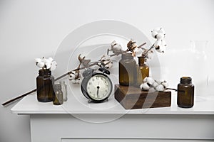 flowers in glass brown small pharmaceutical bottles on white table surface as room decoration. The clock shows six