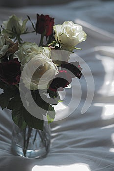 Flowers in a glass vase on white fabric