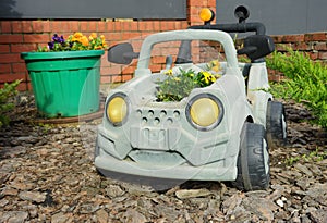 Flowers grow in old plastic car. Reuse things. Creative idea for ecological savety. Environmental protection. Plastic in reuse.