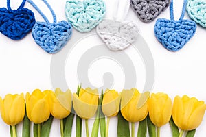 Flowers and hearts lie on a white background. Top view of flat-layed tulips. Floating frame.