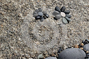 A flowers laid out of pebbles on a stone. Stone garden decors.