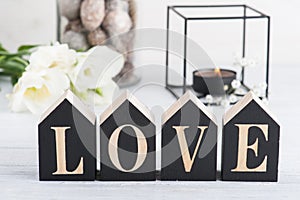 Flowers and lit candle, wooden letter Love