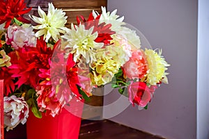 Flowers made of artificial materials in a pink bucket