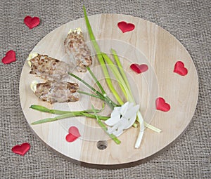 Flowers made of meat on wooden cutting board, red hearts and natural burlap background. Food art idea for Valentine day, birthday