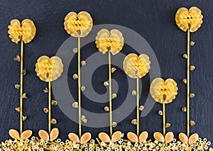 Flowers made out of various pasta on the dark slate background, topview. Flowers made from pasta.