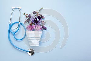 Flowers with mask and stethoscope on blue background. Happy nurse day concept. Top view