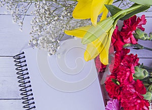 Flowers and notebook on wooden backgrodund