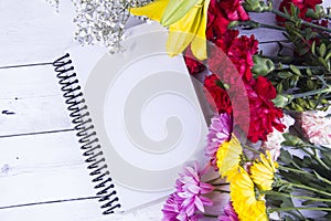 Flowers and notebook on wooden backgrodund