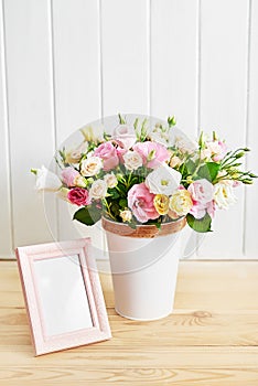 Flowers and photo frame, women`s day. Mother`s day greeting card. Bouquet of flowers eustoma and roses in vase. Happy Birthday!