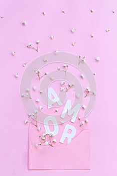 Flowers, pink envelope and word AMOR on a pink background