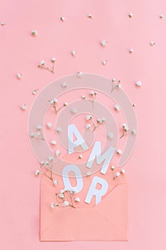 Flowers, pink envelope and word AMOR on a pink background