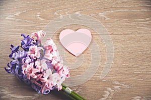 Flowers and pink heart on a wooden table