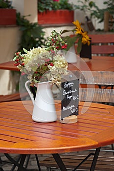 Flowers in pitcher on table.