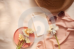 Flowers on the plate with hat, galsses and card on the light background