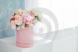 Flowers in round luxury present box. Bouquet of pink and white peonies in paper box near the window.Mock-up of hat box
