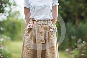 Flowers and shrubs in summer Ornamental garden. girl woman in linen skirt on path of Park.