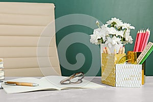 Flowers and stationery on table near chalkboard. Happy teacher`s day