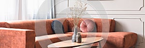 Flowers in stylish dark vase on wooden coffee table in front