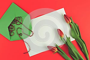 Flowers tulips and green envelope with white card on red background