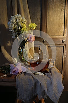 flowers in a vase and a pot of tea on a wooden table