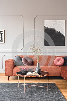 Flowers in vase and red fruits in bowl on wooden coffee table in elegant living room interior