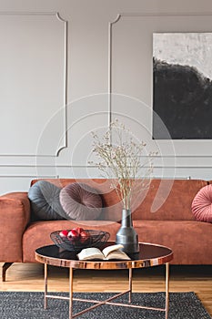 Flowers in vase and red fruits in bowl on wooden coffee table in elegant living room interior