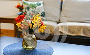 Flowers in a vase in a table by a sofa couch