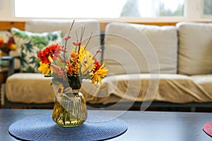 Flowers in a vase on a table by a sofa couch