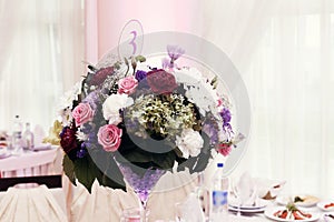 Flowers in vases and numbers of setting at wedding tables with f