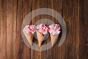 Flowers in a waffle cone. Pink carnations. Flowers on a wooden background