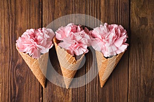 Flowers in a waffle cone. Pink carnations. Flowers on a wooden background