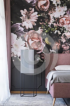 Flowers wallpaper in dark bedroom interior with black table next