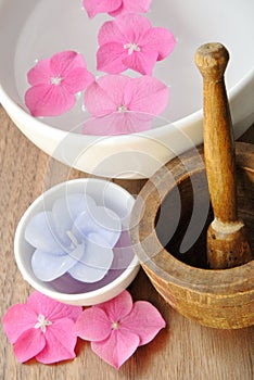 Flowers in a water bowl with candle and a wooden pestle