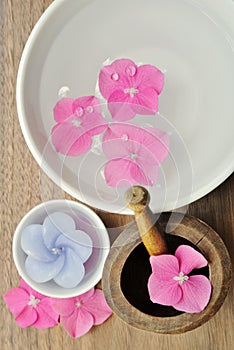 Flowers in a water bowl with a candle and a wooden pestle