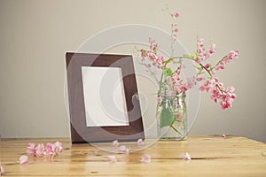 Flowers and white photo frame on wooden table