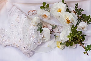 Flowers white wild rose and Golden wedding rings on white pearl color fabric