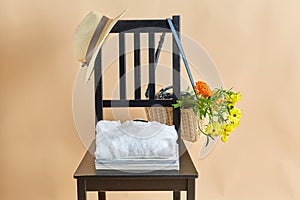 flowers in wicker bag , clothes and hat on chair