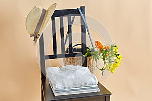 flowers in wicker bag , clothes and hat on chair