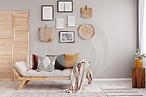 Flowers in yellow vase on wooden stool in beige scandinavian living room interior