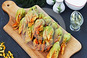 Flowers of zucchini stuffed with cheese are located on a wooden board