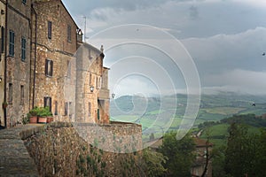 Flowery streets on a rainy spring day in a small magical village Pienza with a view to the Tuscan valley, Tuscany