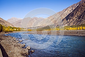 Flowing blue water of Gilgit River with mountains in the background, Pakistan.