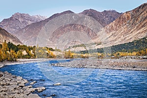 Flowing blue water of Gilgit River with mountains in the background. Pakistan.