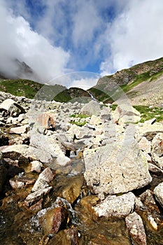 Flowing glacier stream among stones. Caucasus.