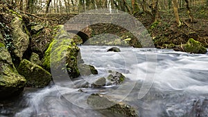 Flowing river in a forest under a brickstone bridge. photo