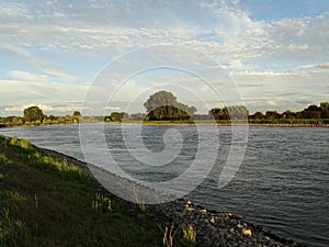 A flowing river with meadows on both sides. the IJssel in the Netherlands
