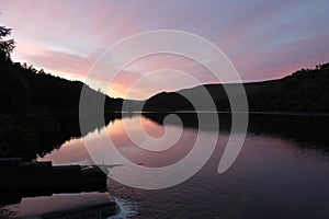 Flowing river reservoir with small waterfall at sunset.Peak district. Derwent Valley.