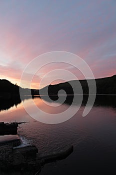 Flowing river reservoir with small waterfall at sunset.Peak district. Derwent Valley.